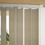 Close-up of beige vertical blind slats and track.
