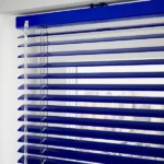 Close-up of blue Venetian blind headrail and slats.