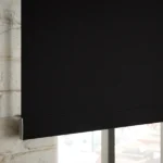 Detail of the bottom bar on a black roller blind.