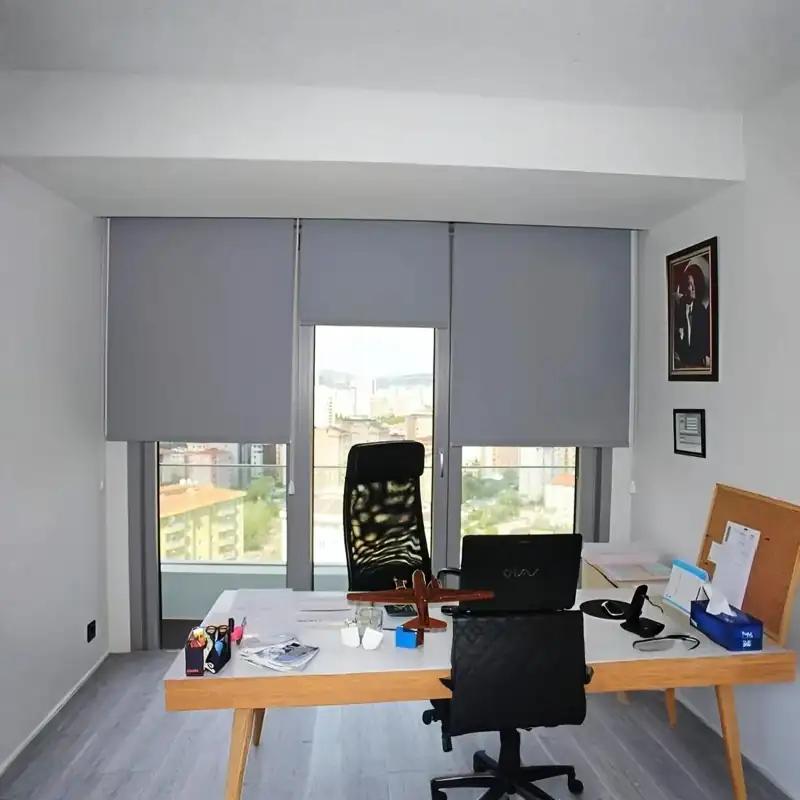Grey blackout roller blinds in a modern home office.