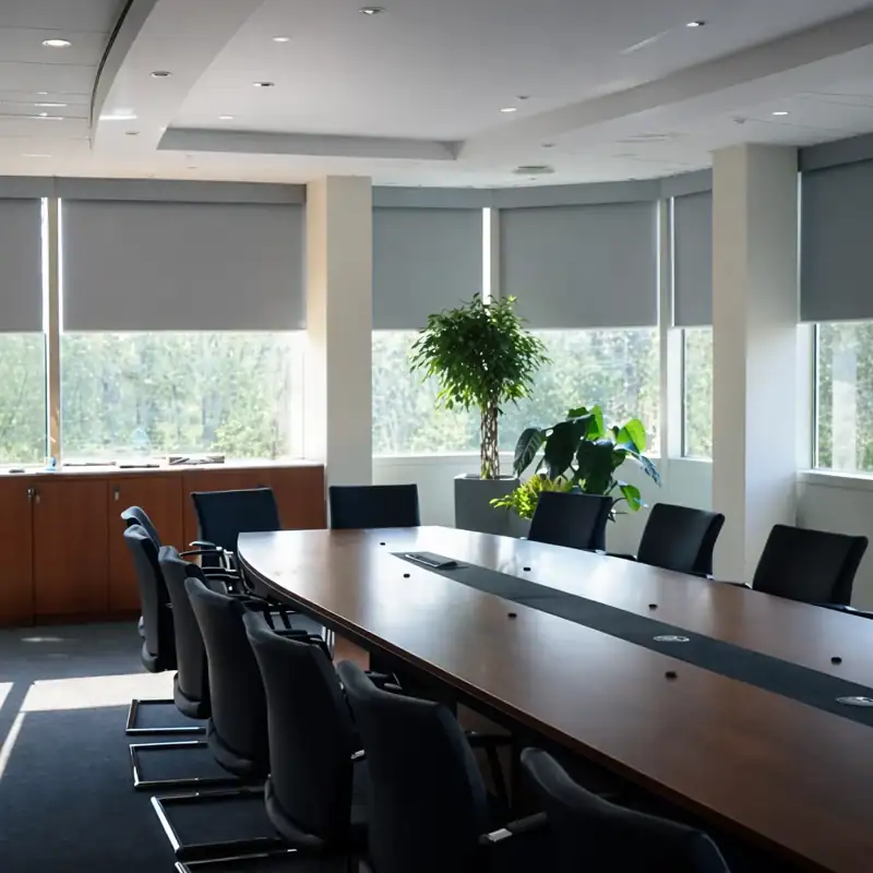 Grey roller blinds in a bright, modern meeting room.