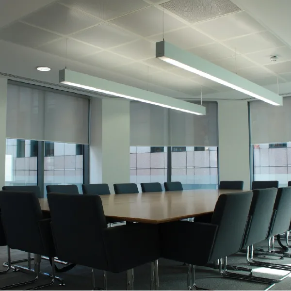 Grey solar roller blinds installed in a minimalist corporate boardroom