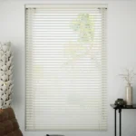 Off-white Venetian blinds on a bright window.