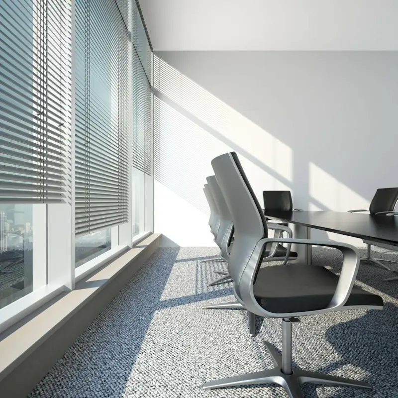 Silver venetian blinds in a sunlit modern boardroom.