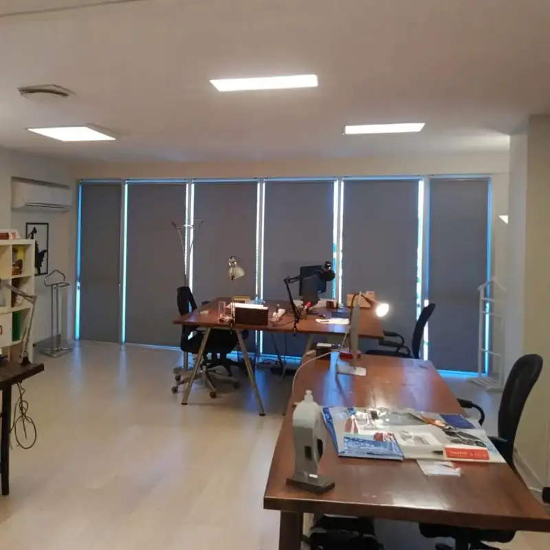 Sleek grey roller blinds in a professional open-plan office.